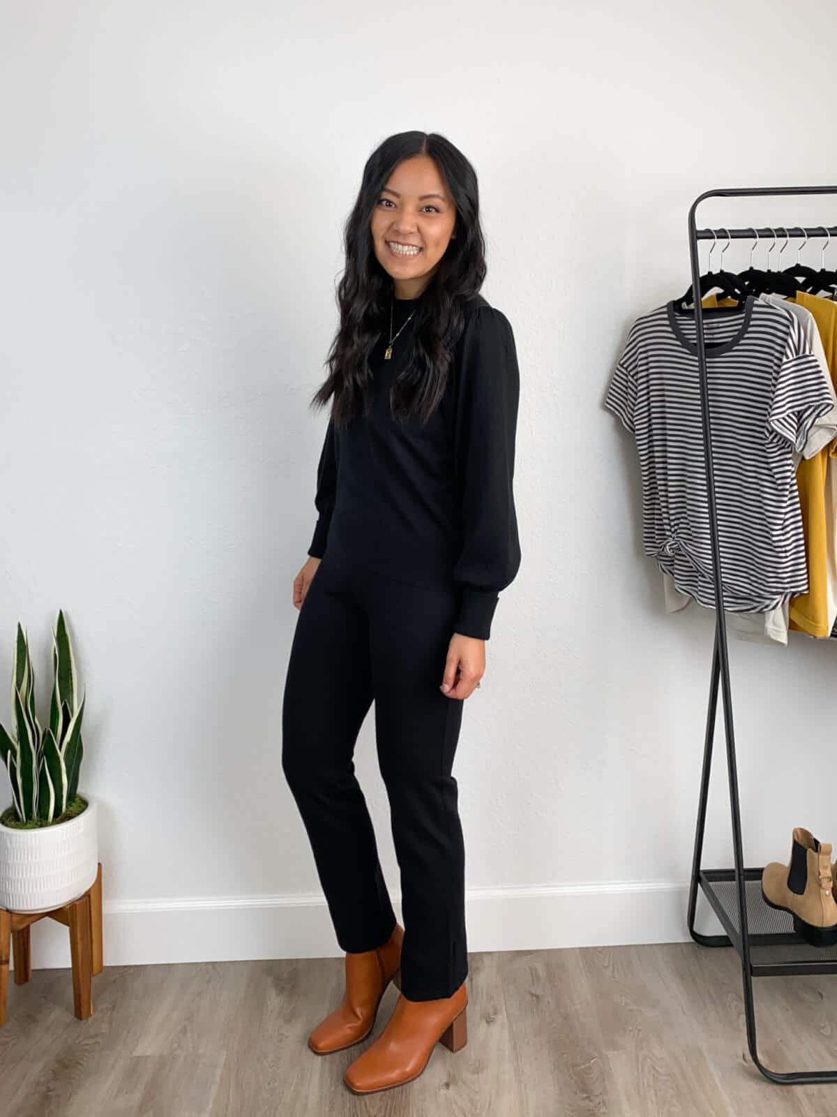 Work Pants with Boots Elevated Business Work Outfit: black puff sleeve sweater + black ankle length straight leg slacks + cognac heeled boots + gold pendant necklace side view